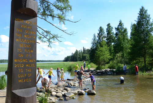 Bucket list-Minnesota Great River Road travelers walking across the Mississippi River headwaters at Lake Itasca